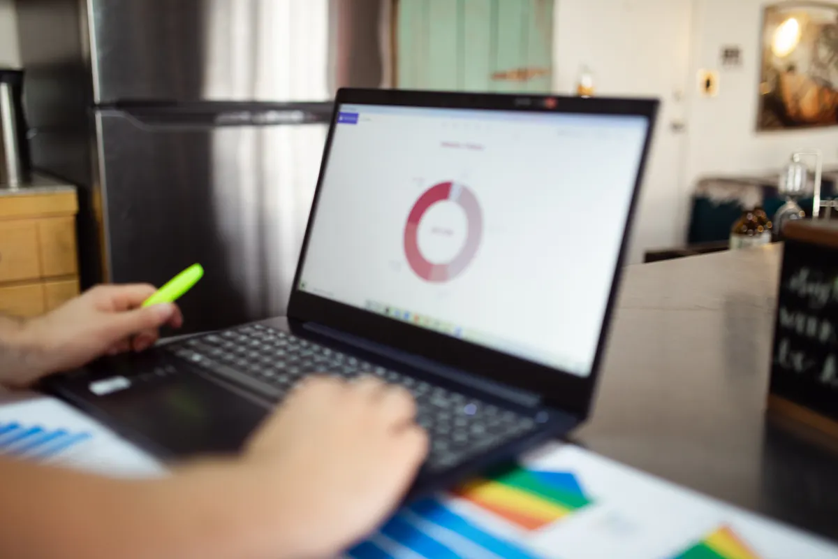 Hand on a laptop showing a dashboard with charts, like an earnings report